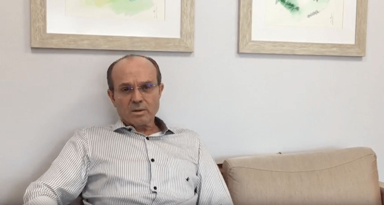 Um homem está sentado em um sofá em frente a duas pinturas.