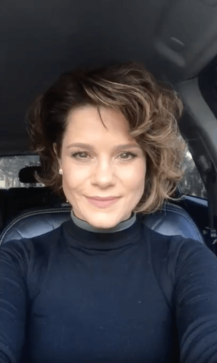 Uma mulher está tirando uma selfie no banco de trás de um carro.