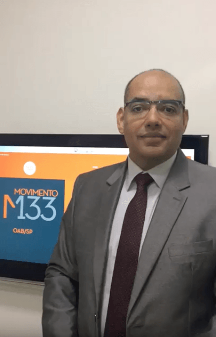 Um homem de terno e gravata está em frente a uma placa que diz m133