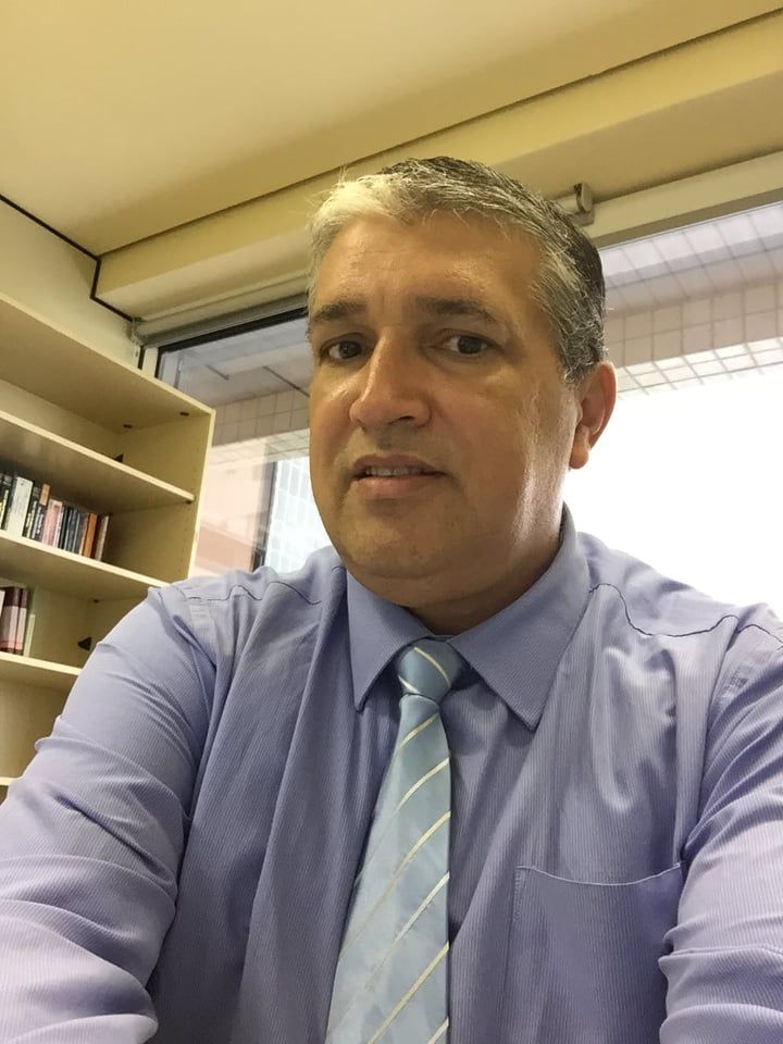 Um homem de camisa azul e gravata está tirando uma selfie.