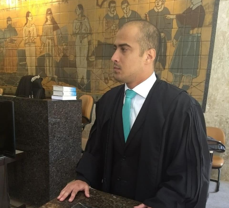 Um homem de terno e gravata está parado em frente a uma pintura