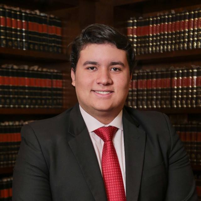 Um homem de terno e gravata está sorrindo na frente de uma estante