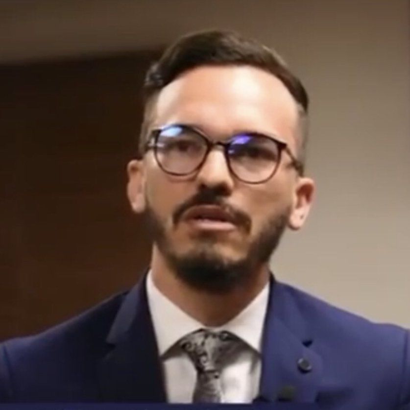 Um homem com barba usando óculos e terno