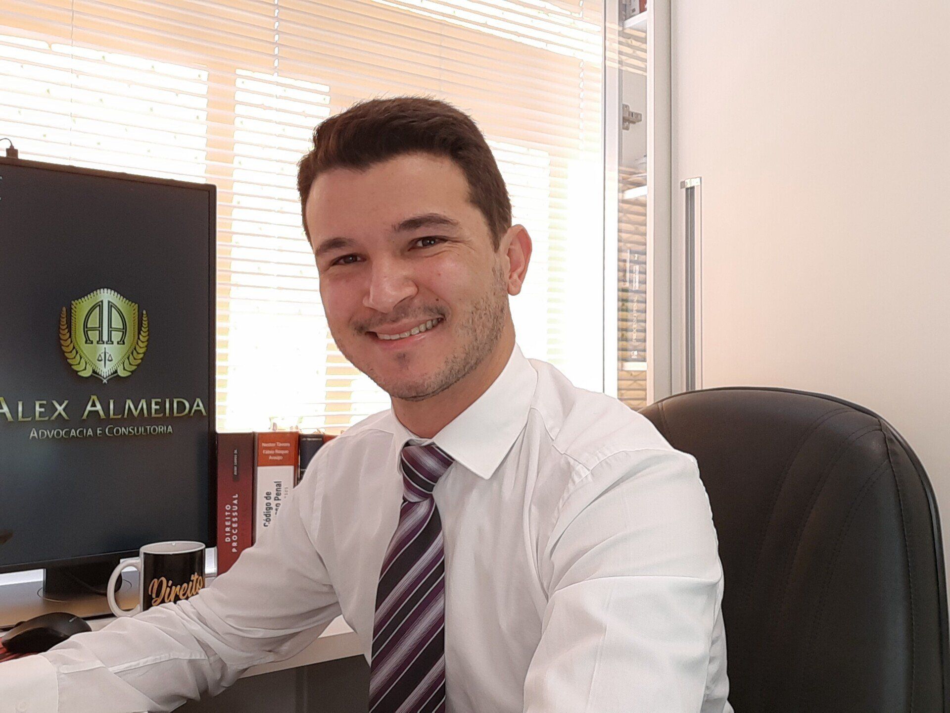 Um homem de camisa branca e gravata está sentado em uma mesa.