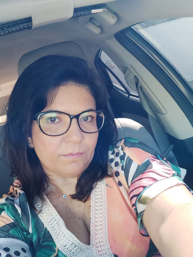 Uma mulher de óculos está tirando uma selfie em um carro.