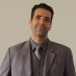 Um homem de terno e gravata está sorrindo para a câmera.