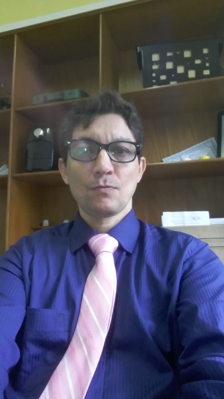 Um homem de óculos e gravata rosa está tirando uma selfie