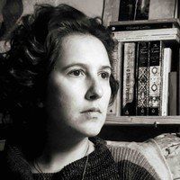 Uma mulher está sentada em um sofá em frente a uma estante.