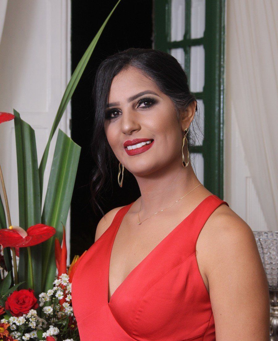 Uma mulher de vestido vermelho está sorrindo na frente de flores