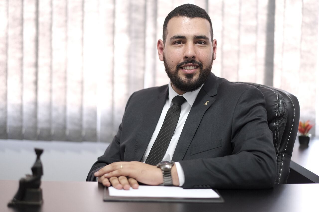 Um homem de terno e gravata está sentado em uma mesa.