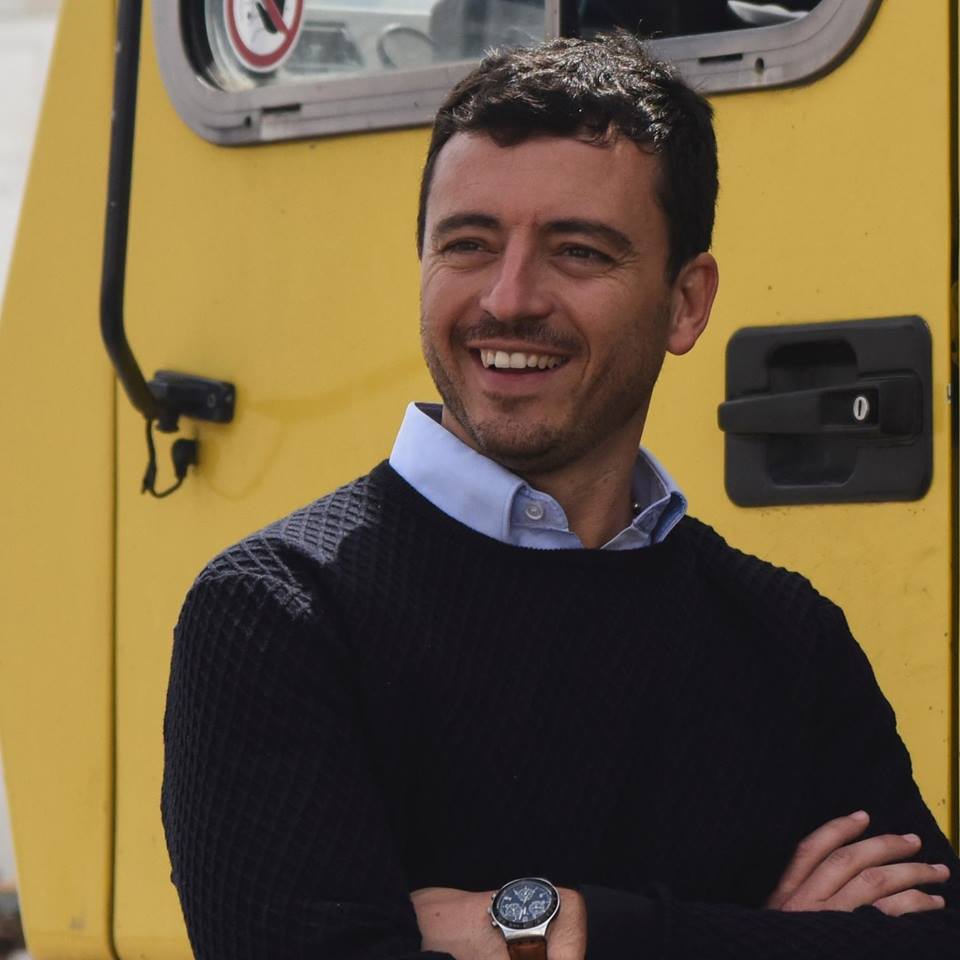 Um homem usando um relógio está sorrindo na frente de uma van amarela