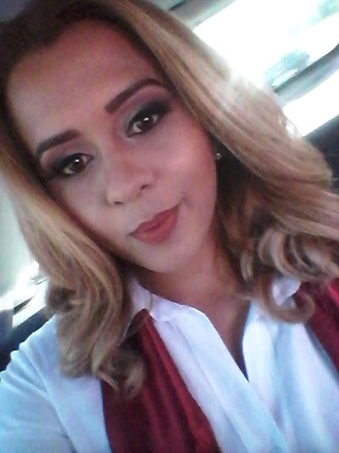 Uma mulher de camisa branca e lenço vermelho está tirando uma selfie.