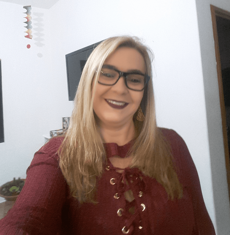 Uma mulher de óculos e camisa vermelha sorri para a câmera