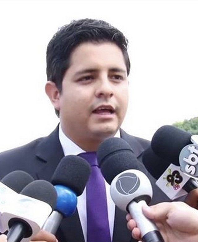 Um homem de terno e gravata é cercado por microfones, incluindo um que diz sbt