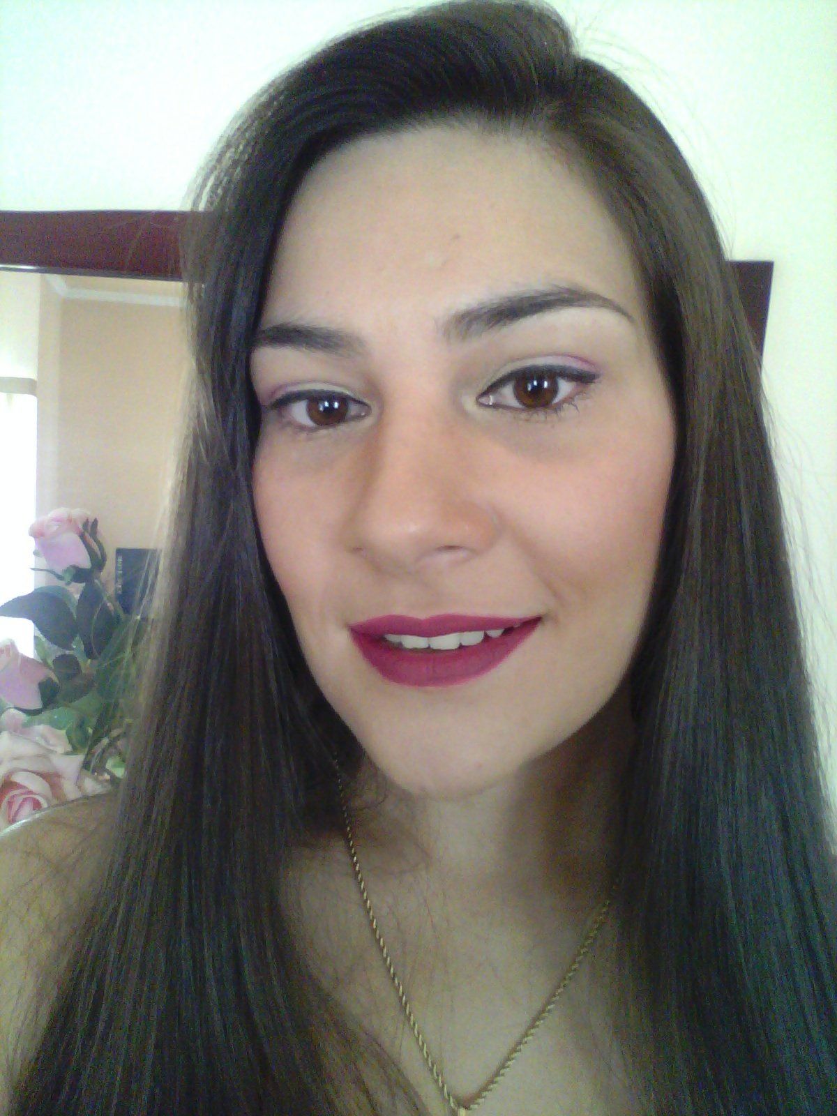 Um close do rosto de uma mulher com cabelos longos e um colar.