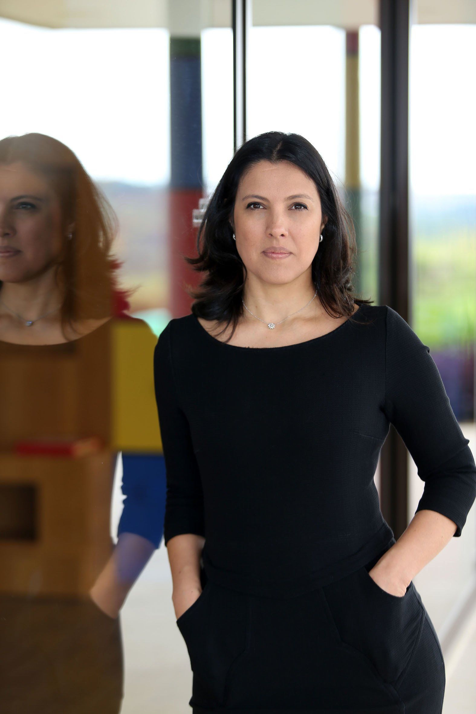 Uma mulher de vestido preto fica com as mãos nos bolsos