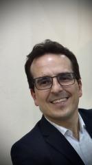 Um homem de óculos e terno está sorrindo para a câmera.