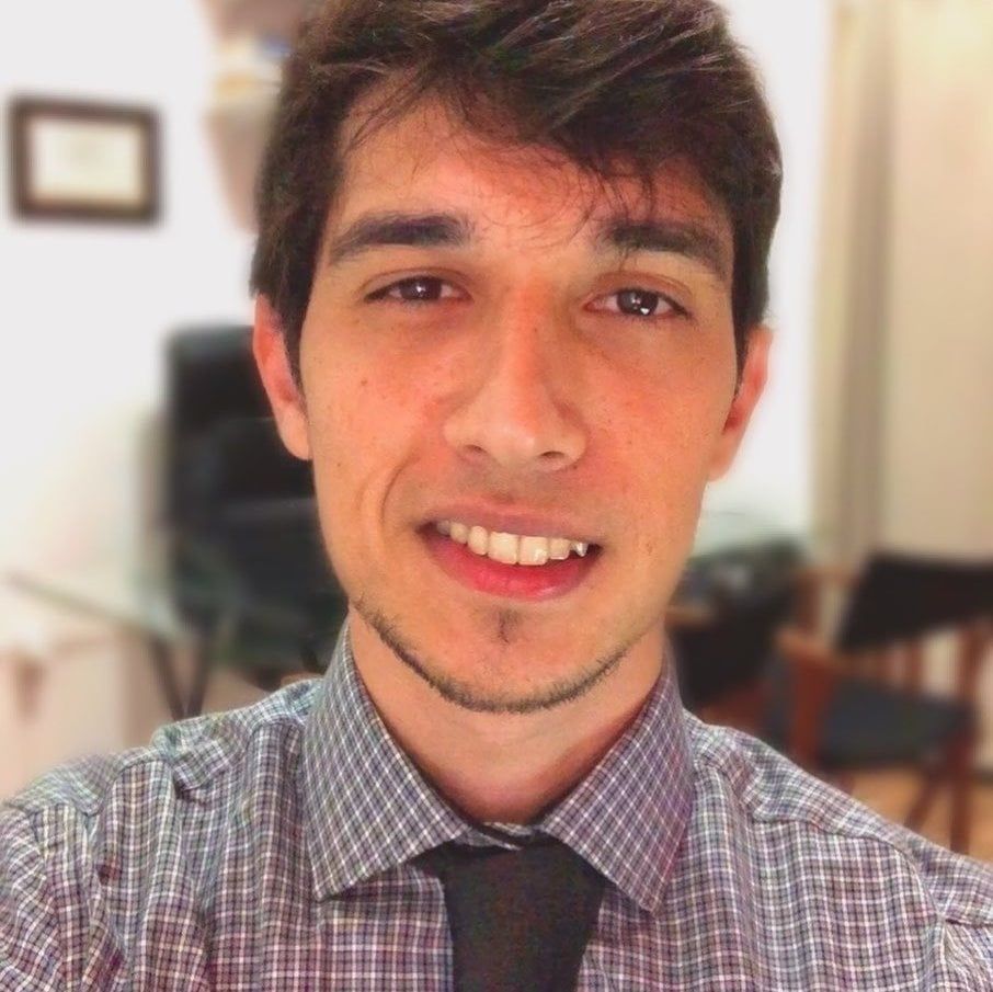 Um homem de camisa xadrez e gravata sorri para a câmera