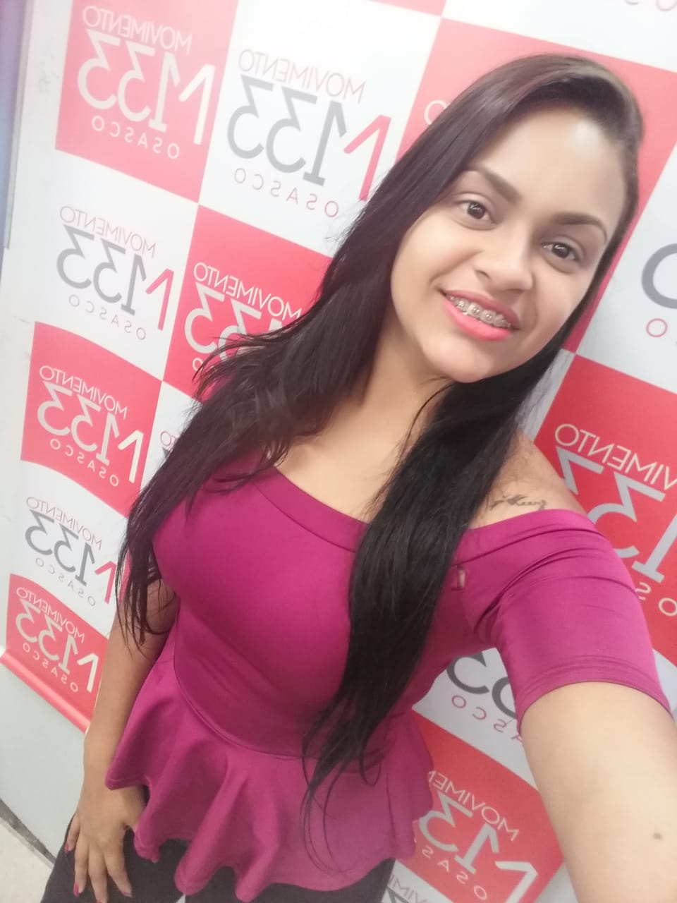 Uma mulher tirando uma selfie em frente a uma parede que diz eem