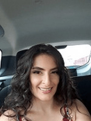 Uma mulher está sorrindo enquanto está sentada no banco de trás de um carro.