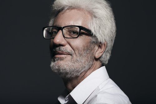 Um homem de óculos e barba está vestindo camisa branca e gravata.