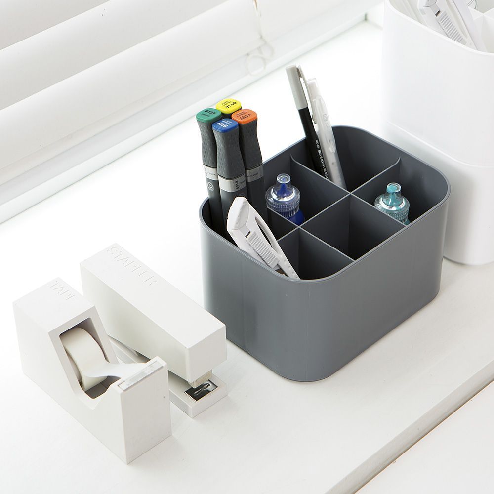 Una mesa con un portalápices y un dispensador de cinta adhesiva.