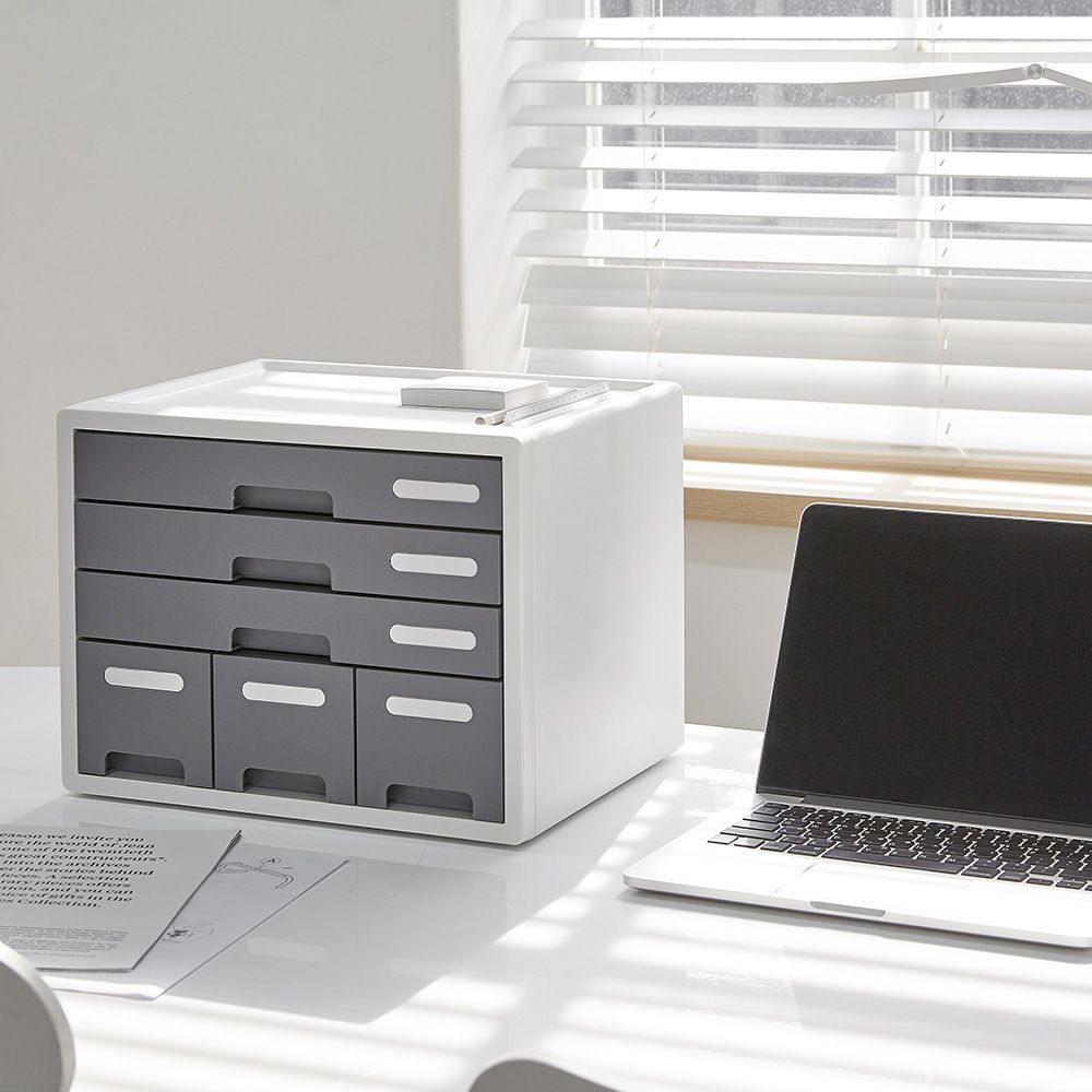 Un ordenador portátil está sobre una mesa junto a un cajón.