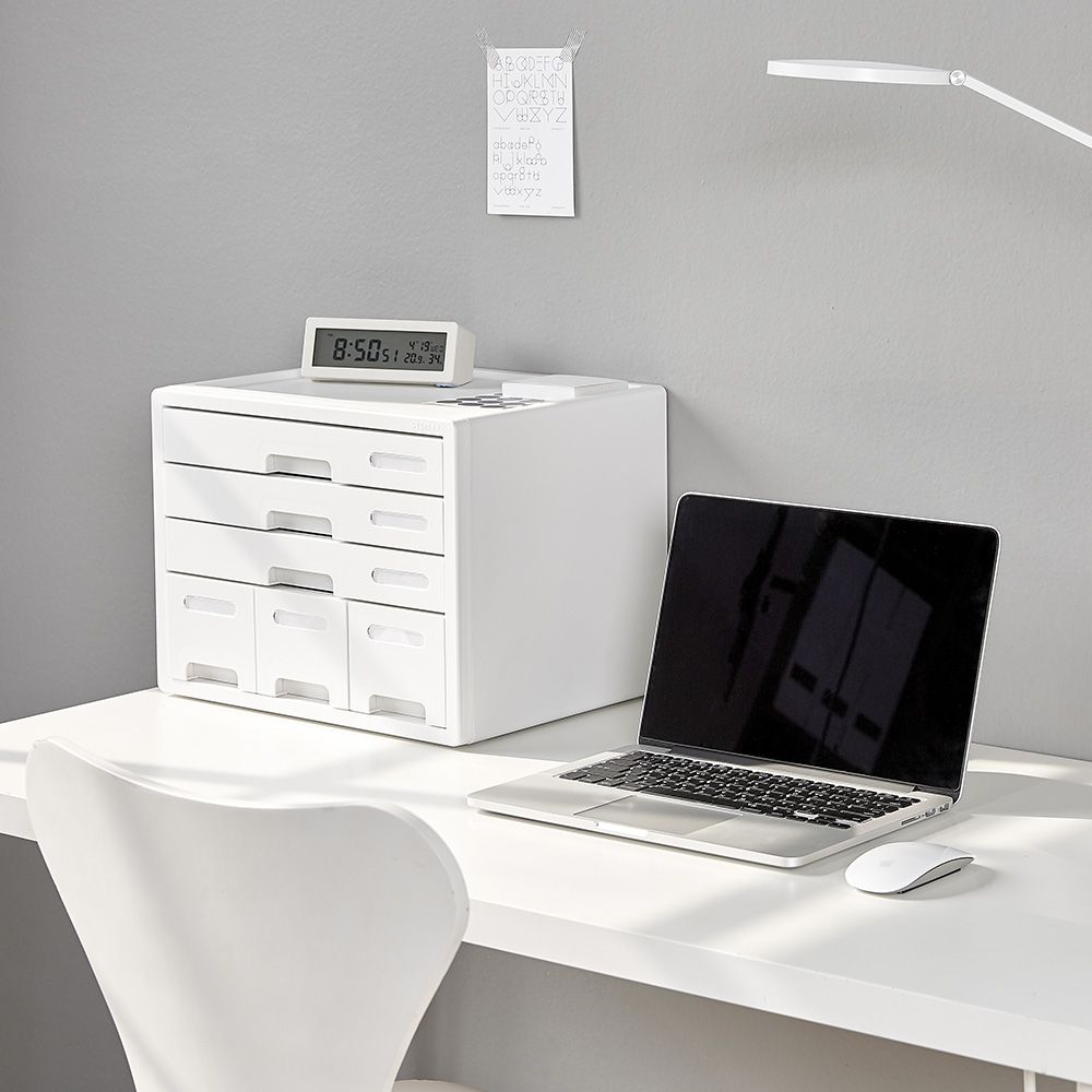 Una mesa con un ordenador portátil y un reloj encima.