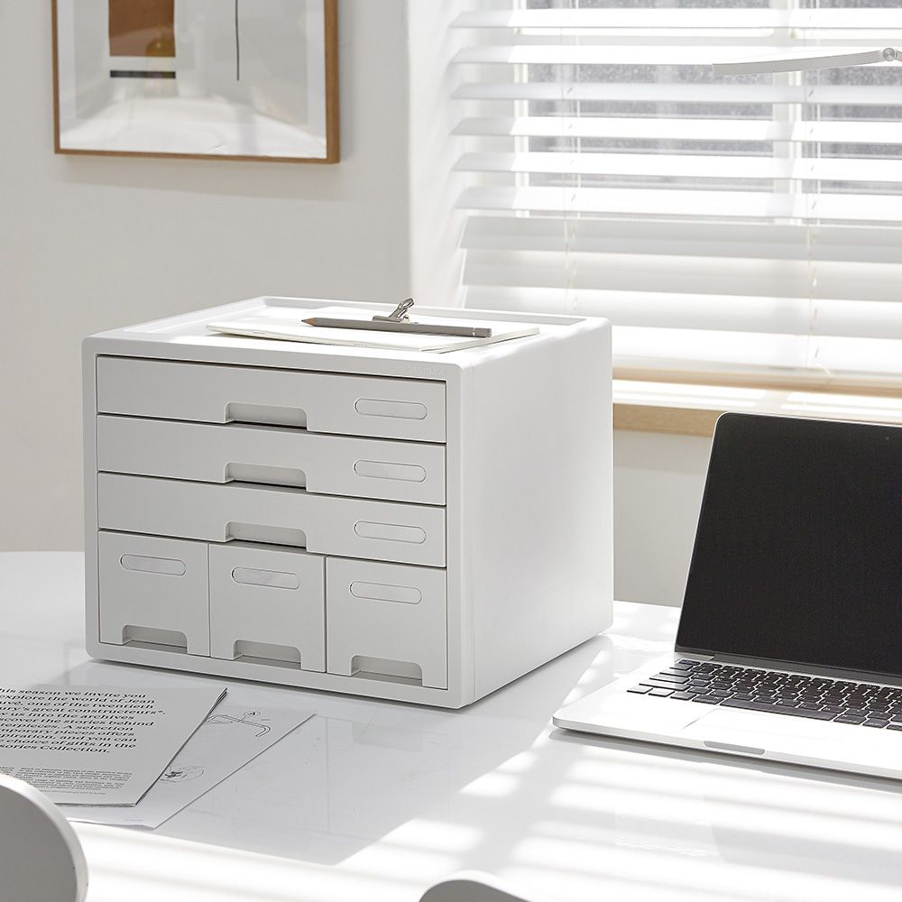 Hay un armario blanco sobre una mesa junto a un ordenador portátil.