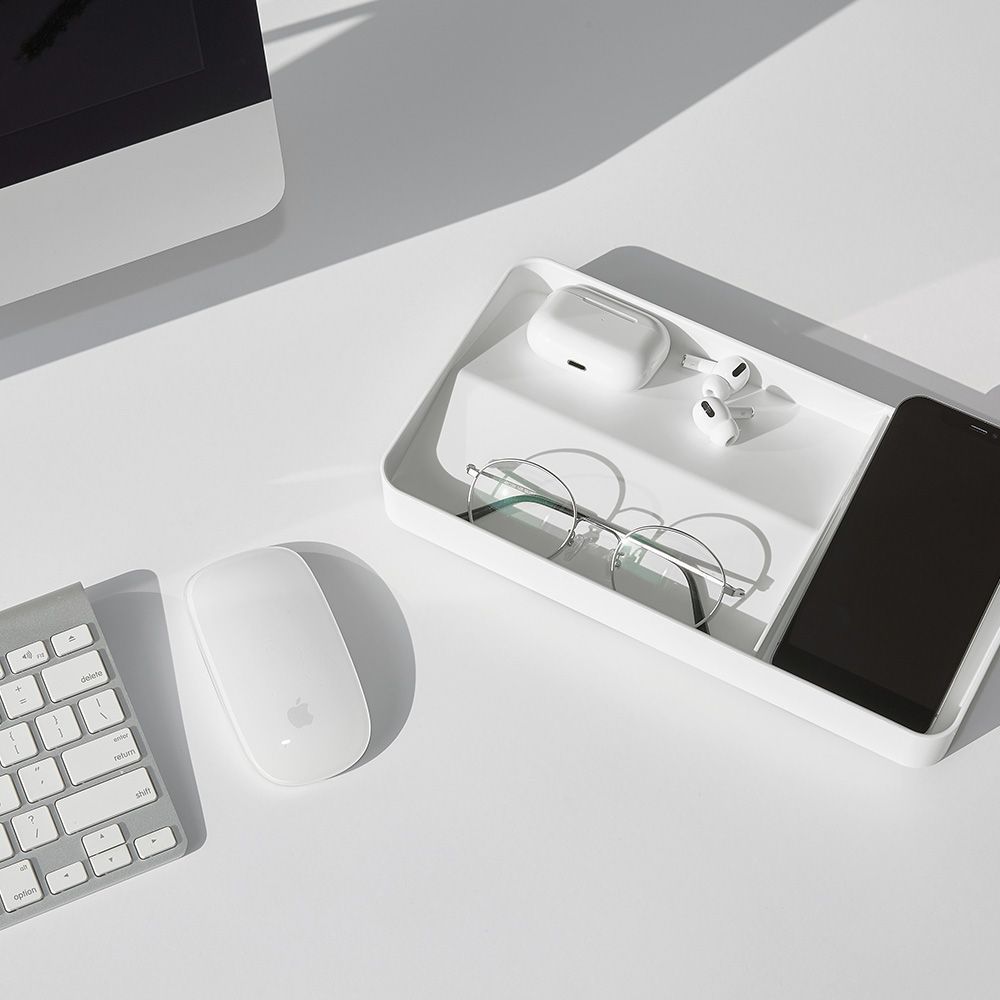 Una bandeja blanca con un teléfono, gafas y auriculares.