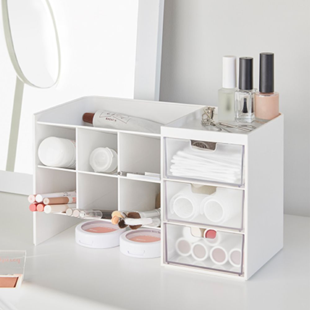 Una cómoda blanca con cajones llenos de maquillaje y pinceles.