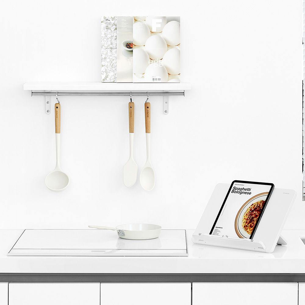 Una encimera de cocina con una olla, cucharas y un libro encima.