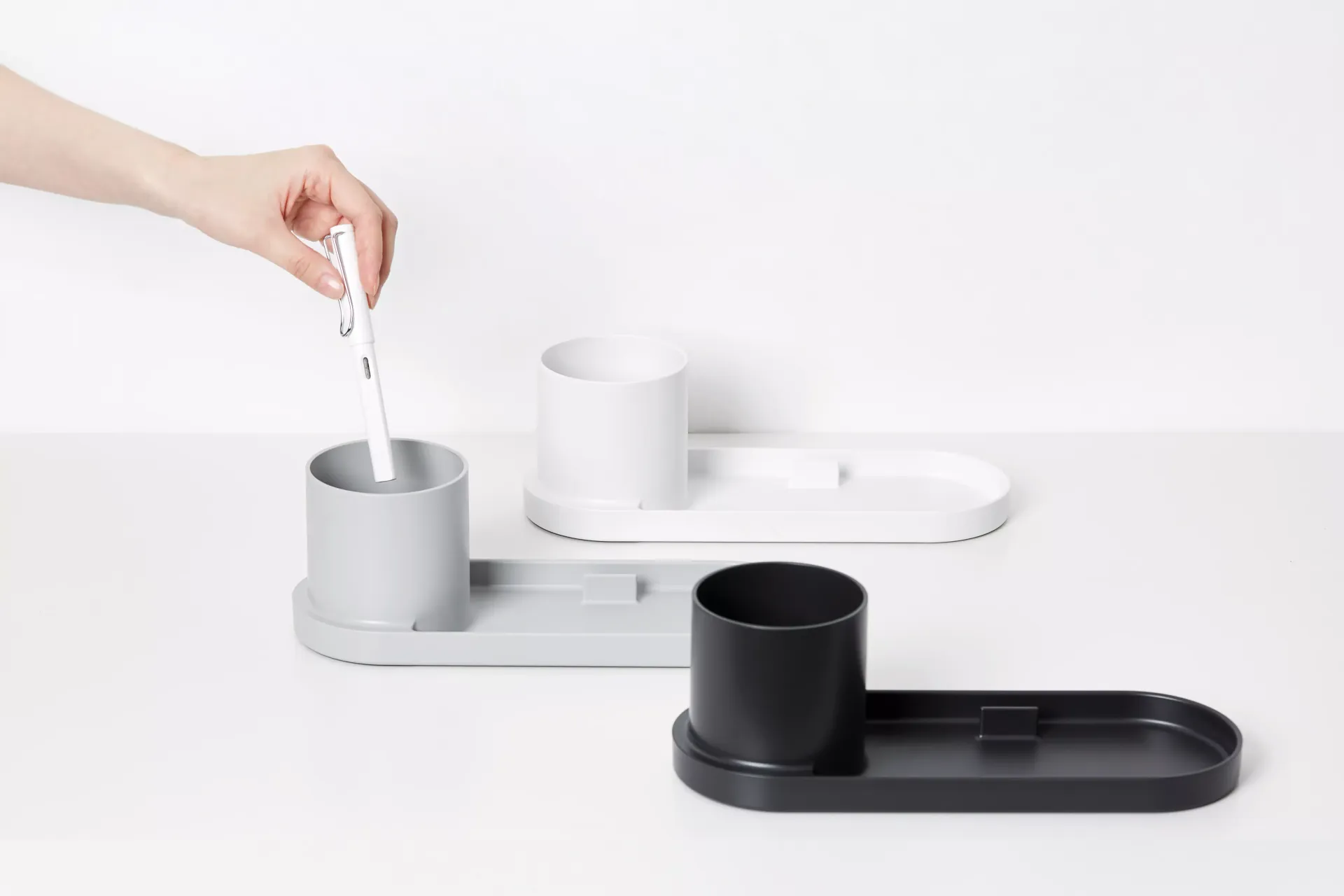 Una persona sostiene un cepillo de dientes en un vaso sobre una mesa.