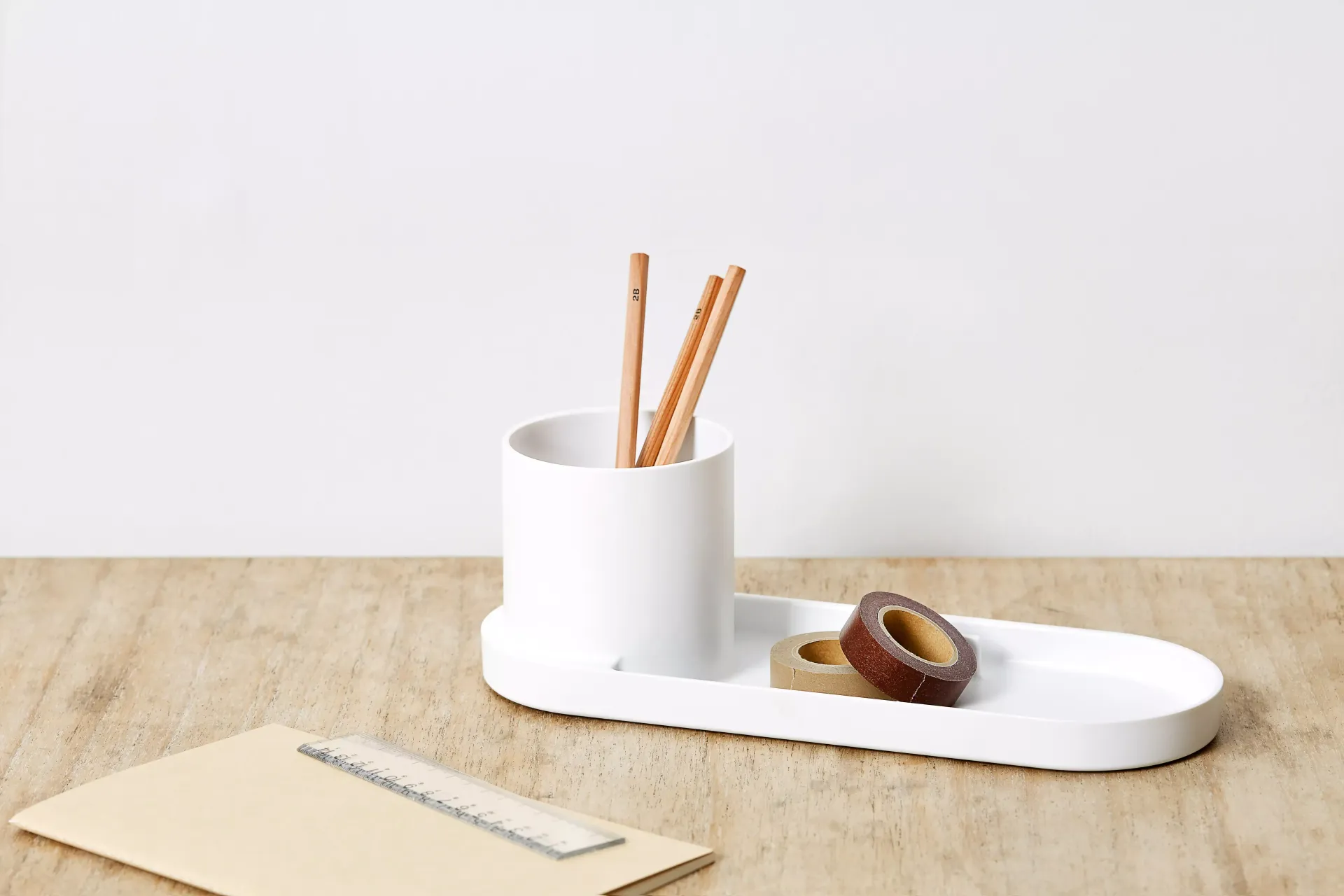 Una bandeja blanca con lápices y cinta adhesiva.