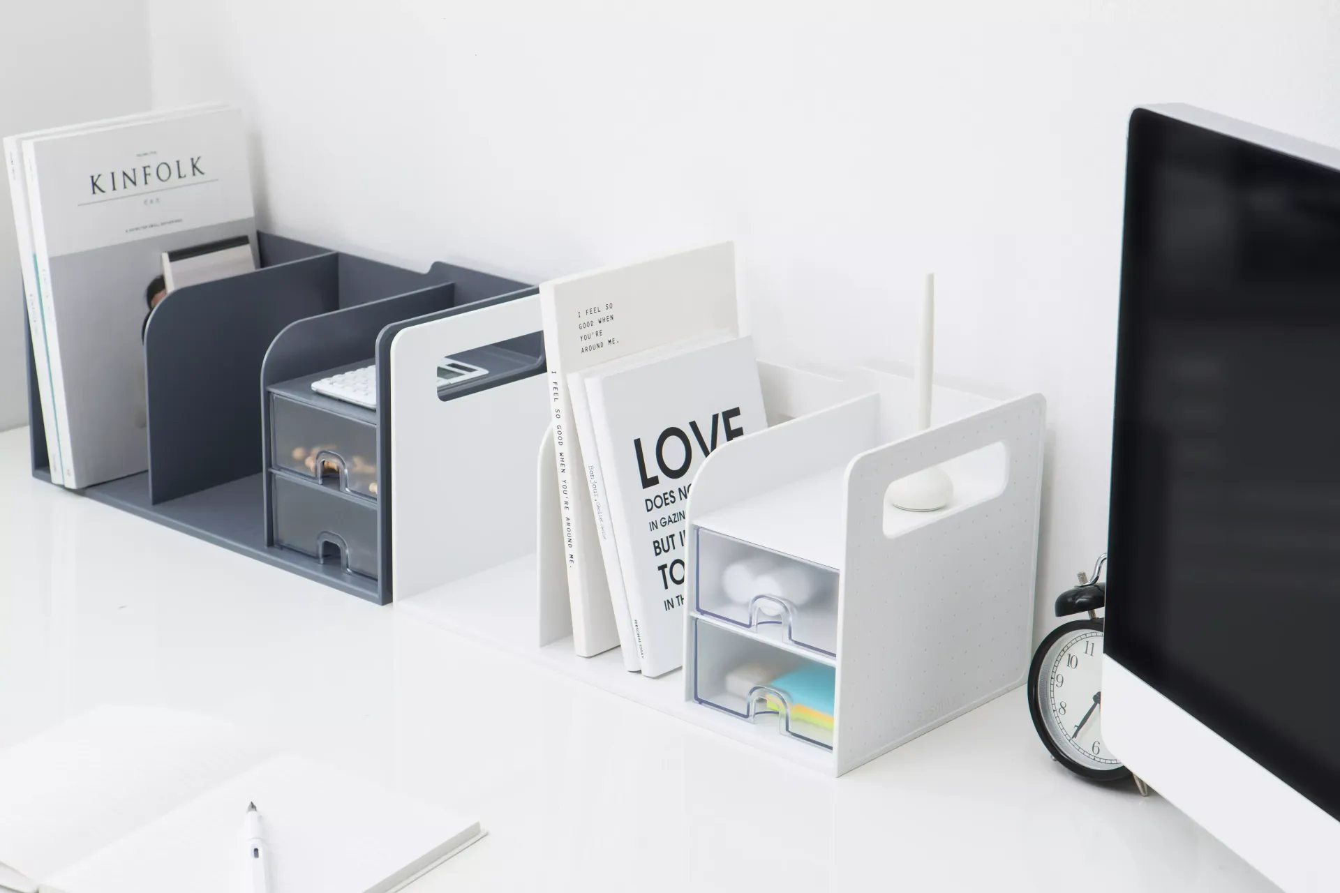 Una mesa con un ordenador, libros y un reloj.