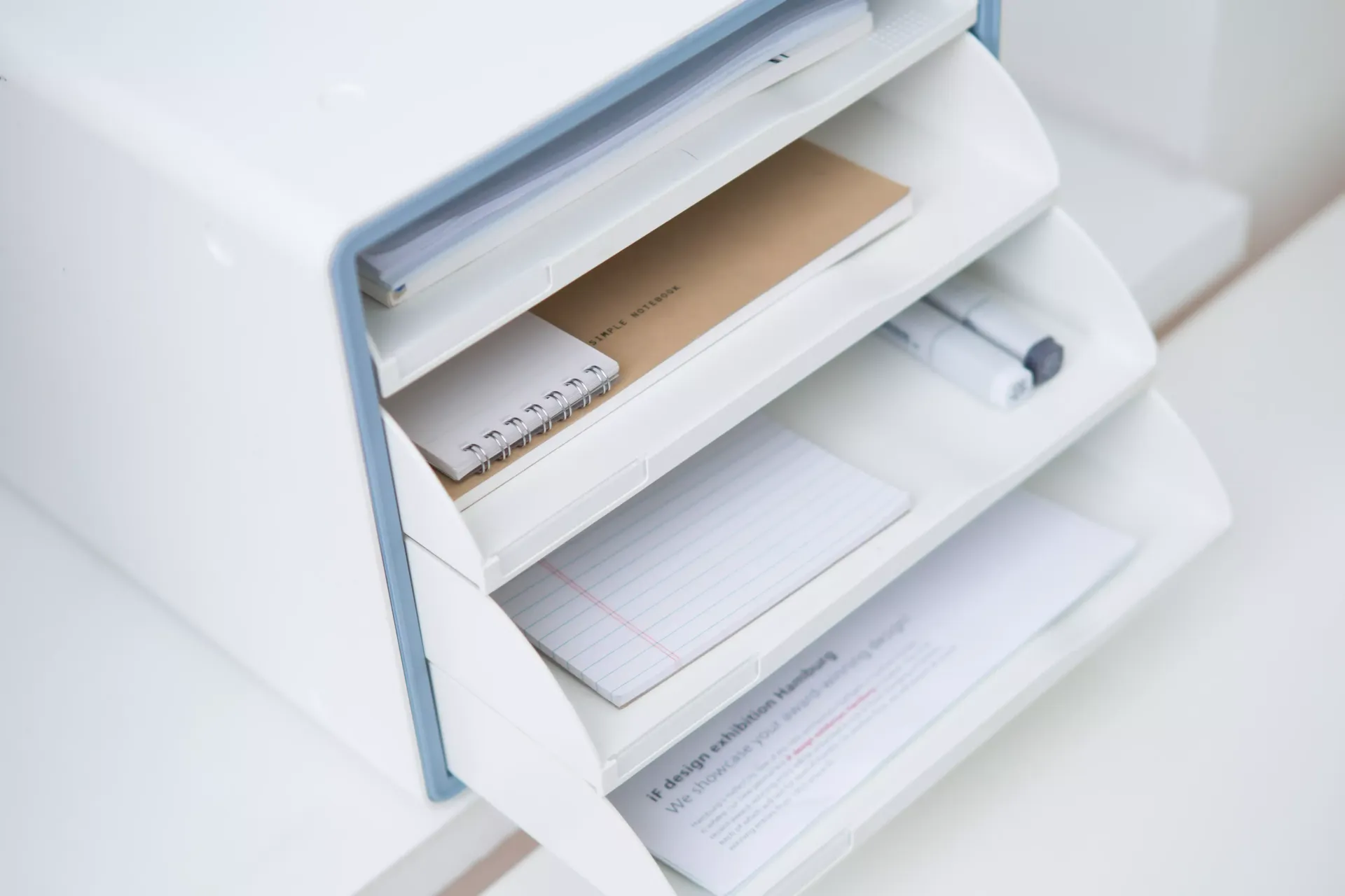 Un organizador de escritorio con cajones con papeles y un cuaderno encima.