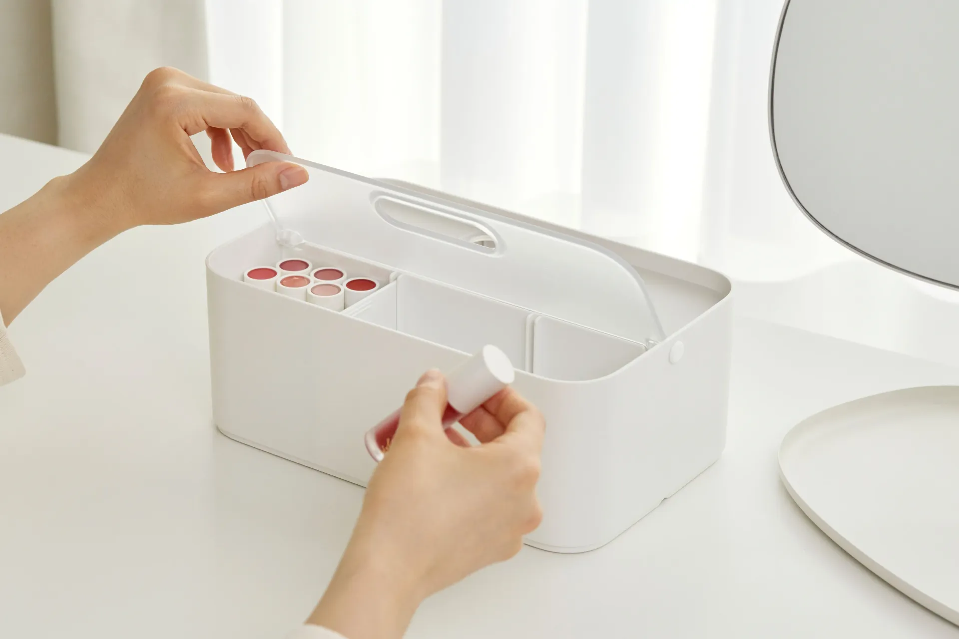 Una persona sostiene un frasco de pintalabios en una caja blanca.