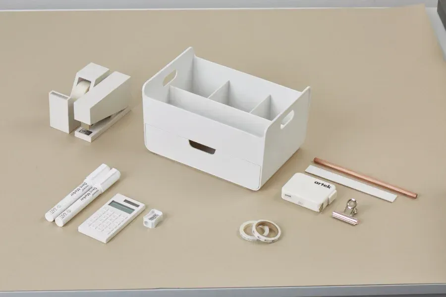 Una mesa con una caja y un montón de material de oficina encima.