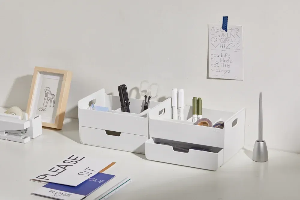 Una mesa con dos cajas blancas llenas de varios objetos.