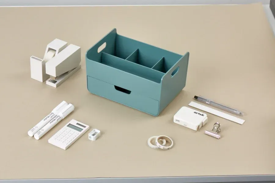 Una mesa con una caja y un montón de material de oficina encima.