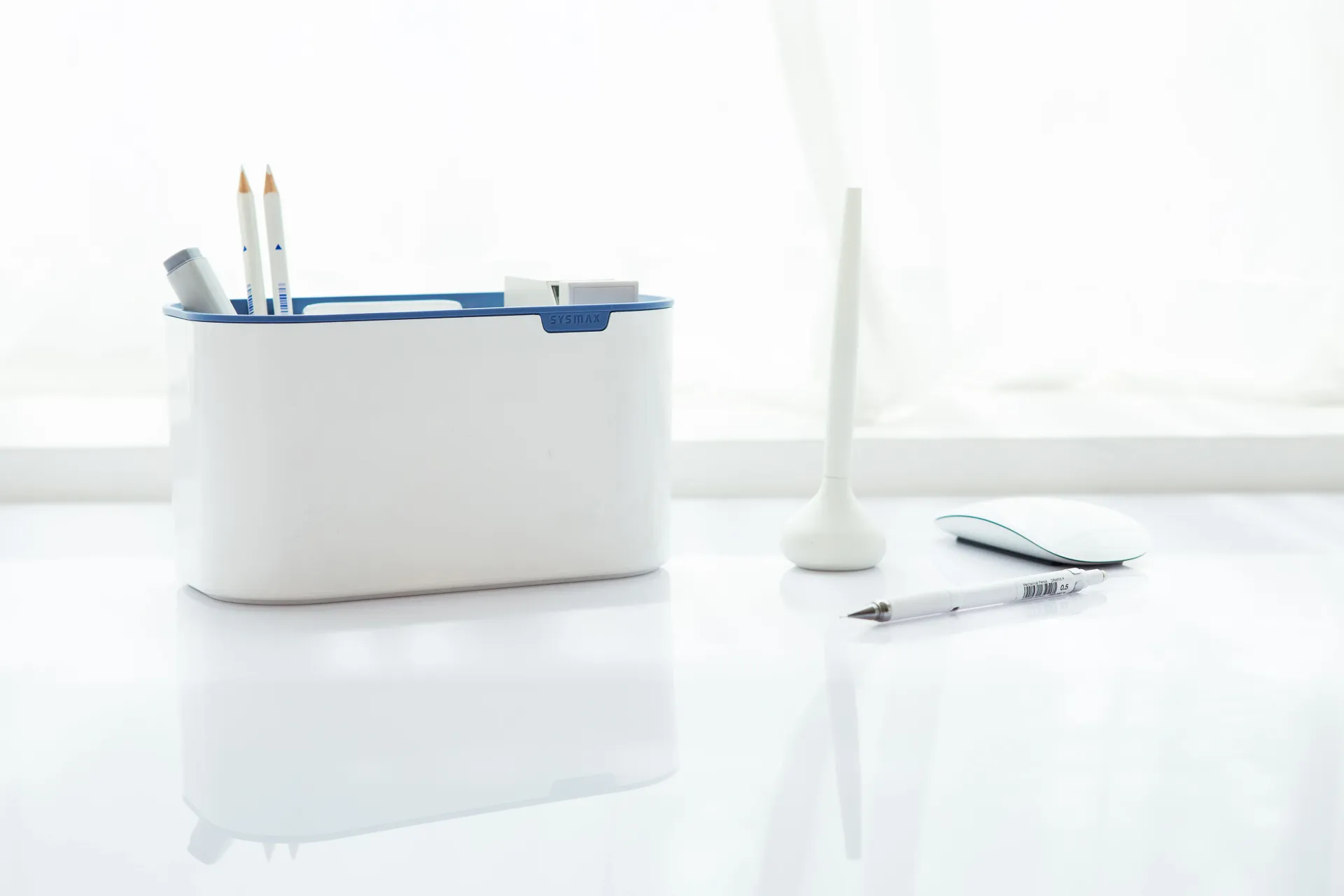 Un portalápices blanco y azul está sobre una mesa blanca.