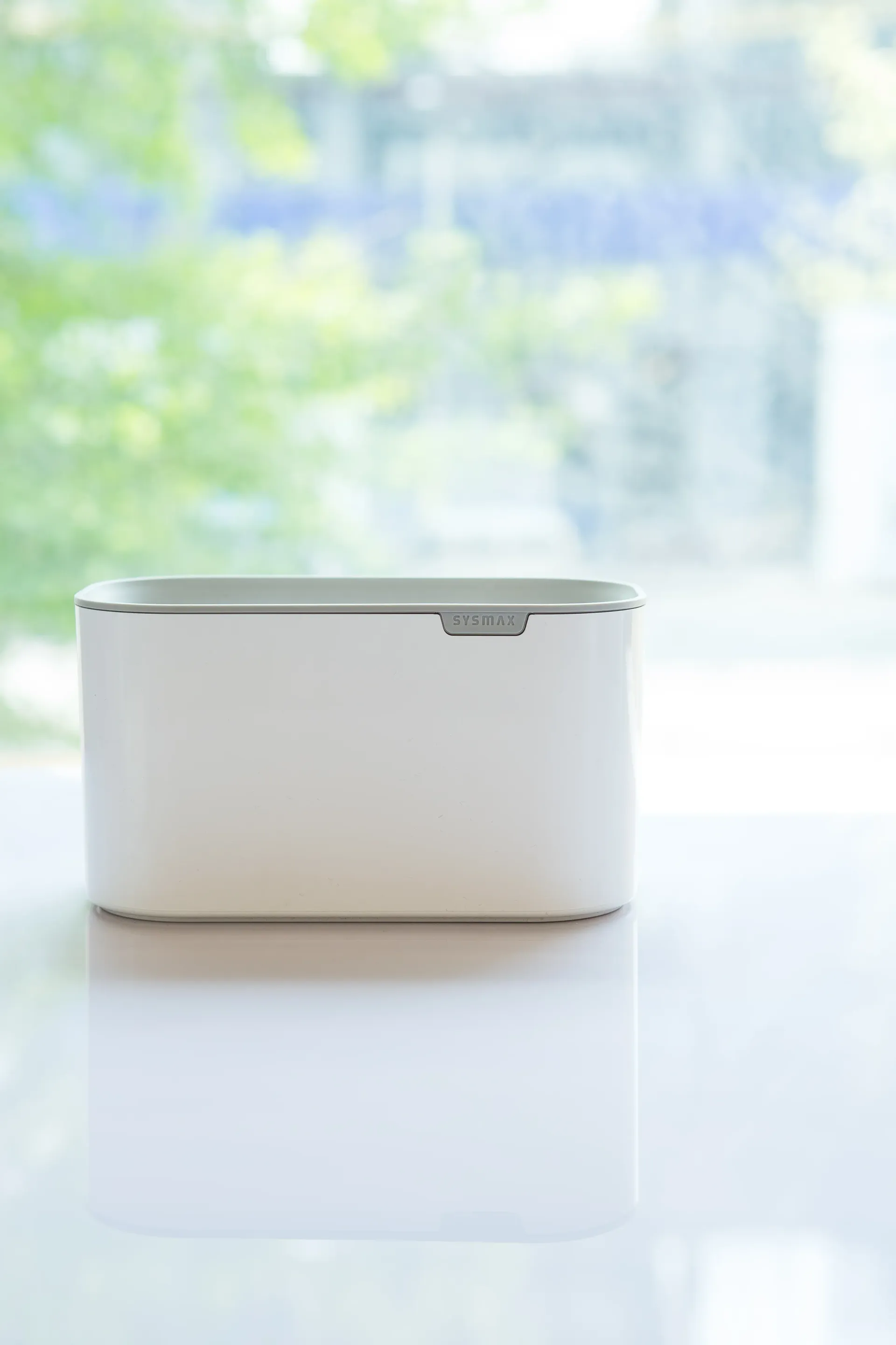 Un portalápices blanco sobre una mesa blanca frente a una ventana.