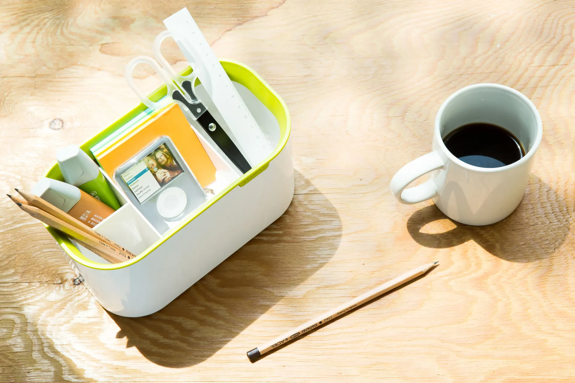 Secretaria con un lápiz, una taza con café y un portalápices con varios objetos.