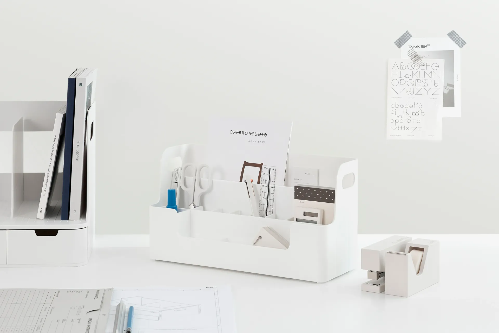 Una mesa blanca con una caja blanca llena de material de oficina.