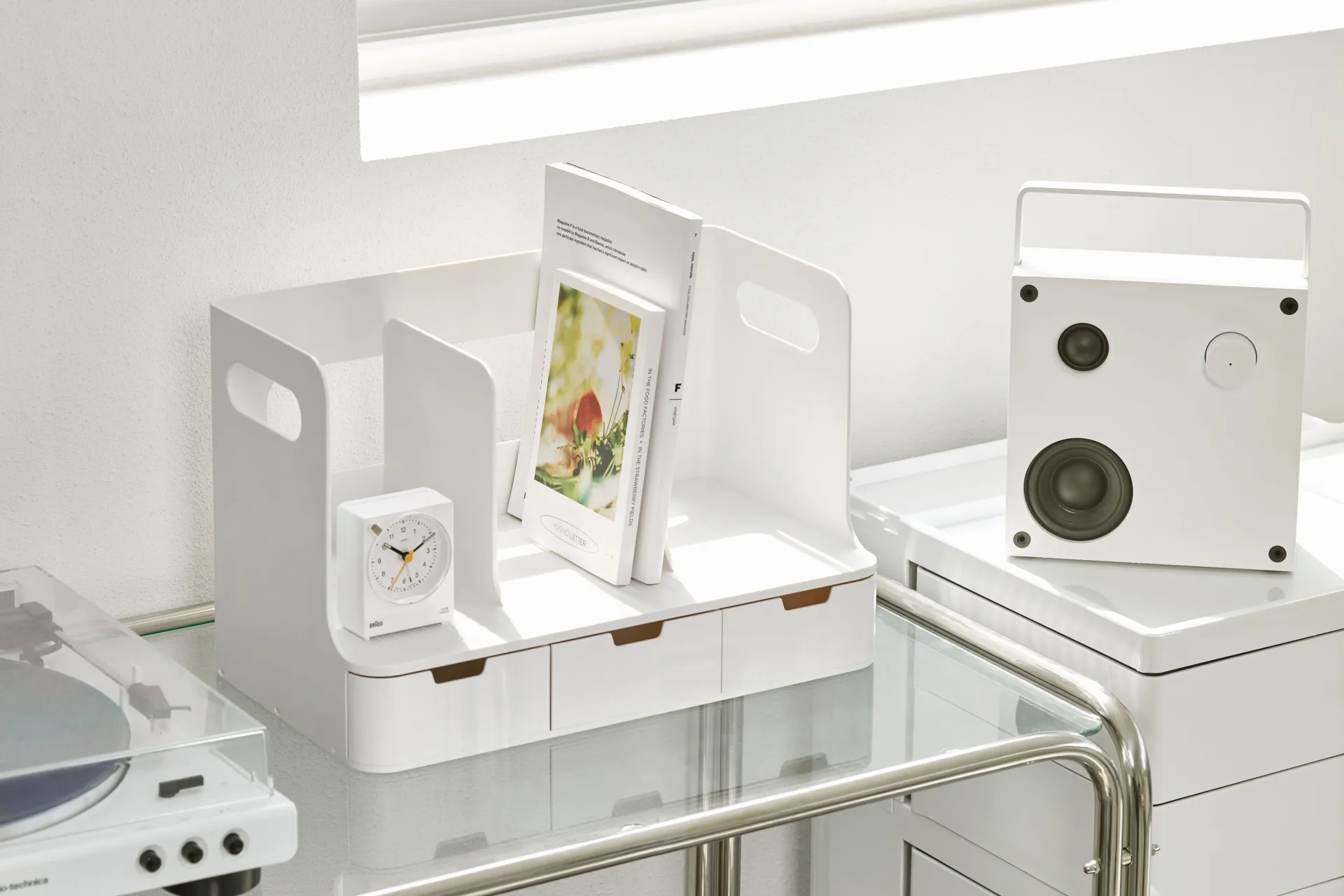 Una estantería blanca con un reloj y un altavoz encima.