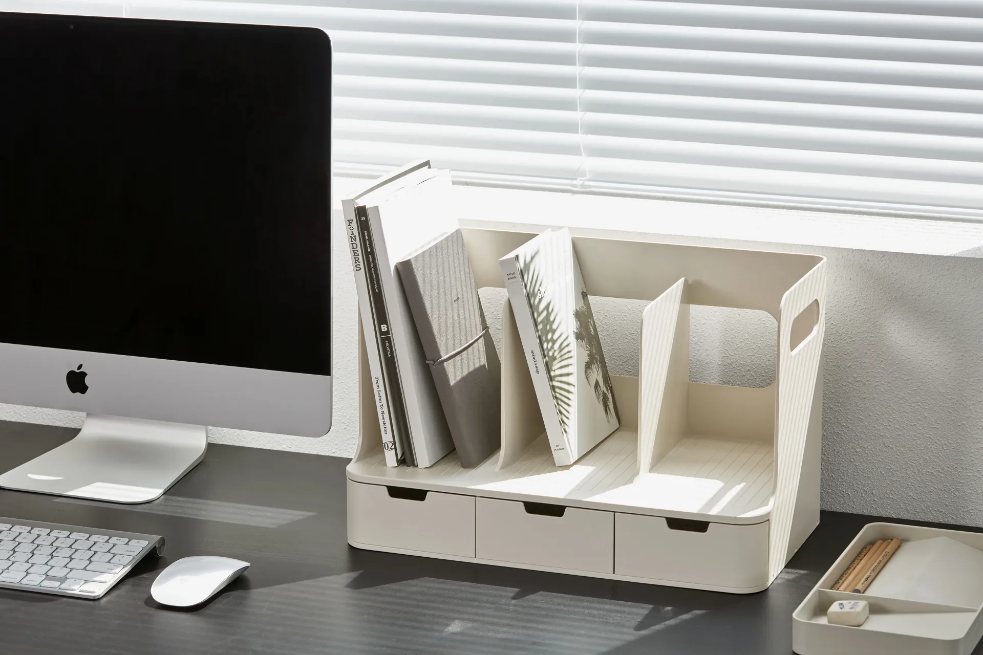 Hay un ordenador sobre una mesa junto a una estantería.