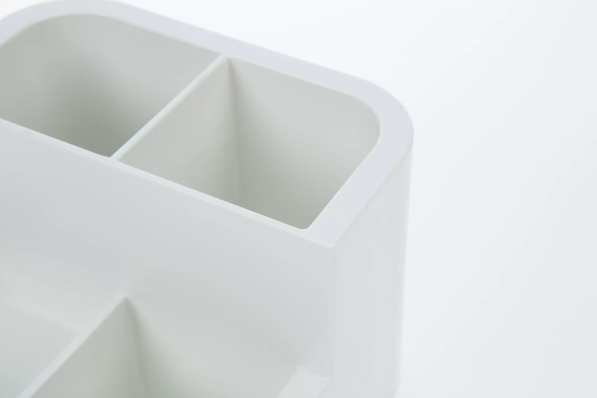 Un recipiente de plástico blanco con tres compartimentos sobre un fondo blanco.