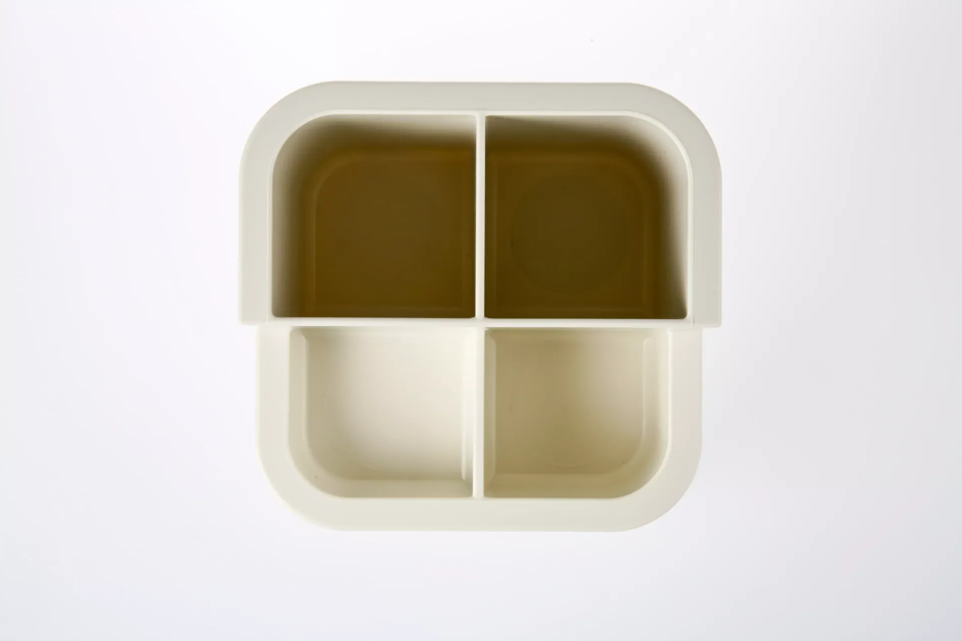 Un recipiente blanco con cuatro compartimentos sobre un fondo blanco.