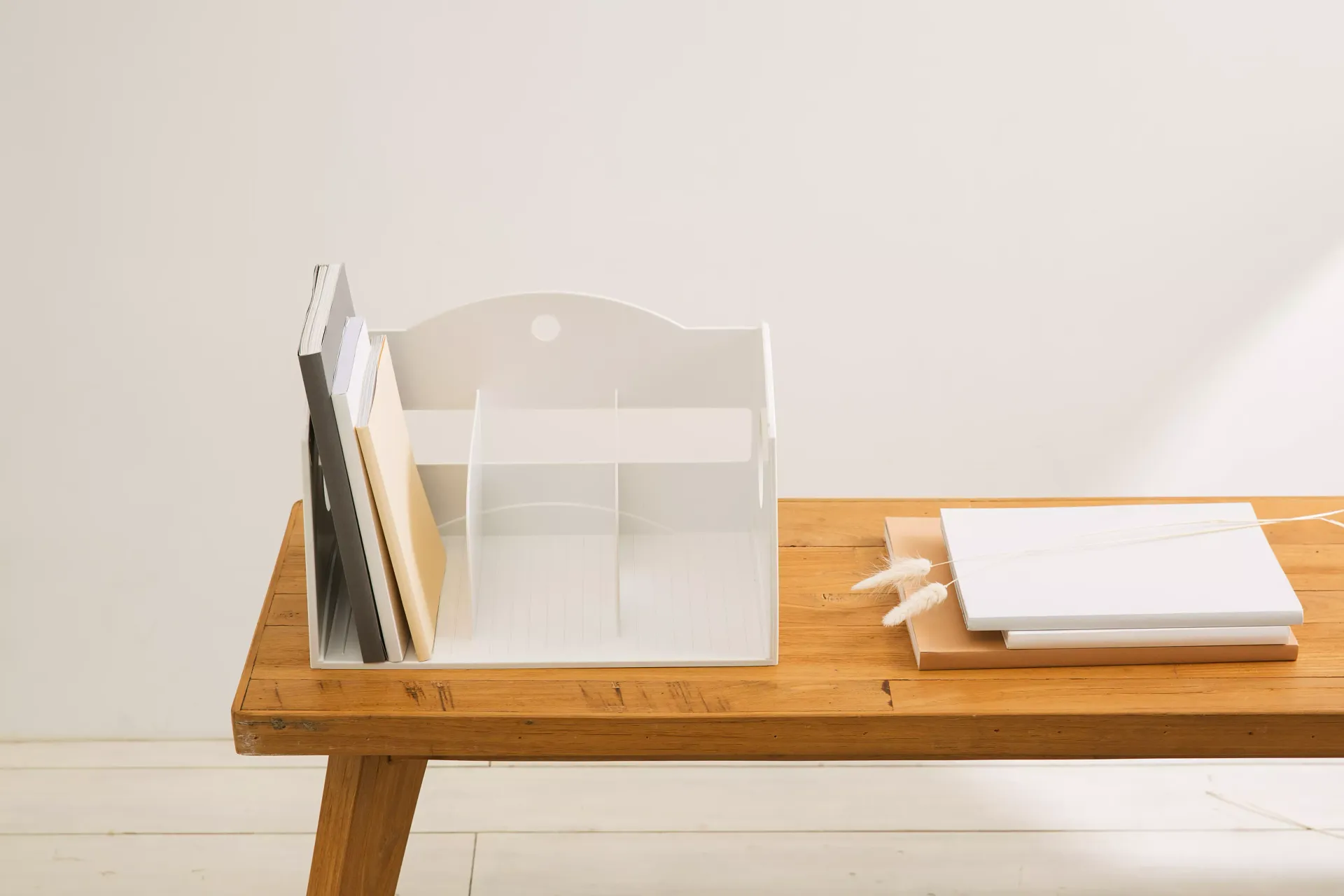 Una mesa de madera con un organizador blanco y un ordenador portátil encima.