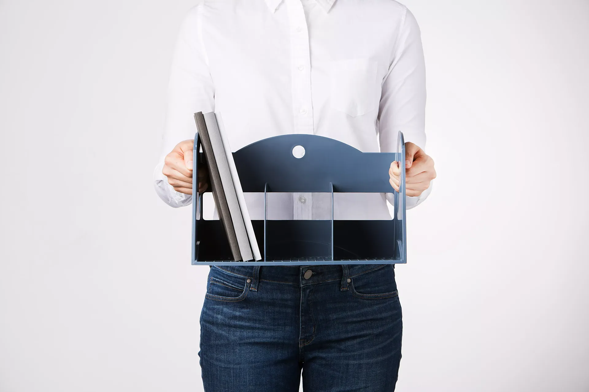 Una mujer con camisa blanca y vaqueros azules sostiene un atril.